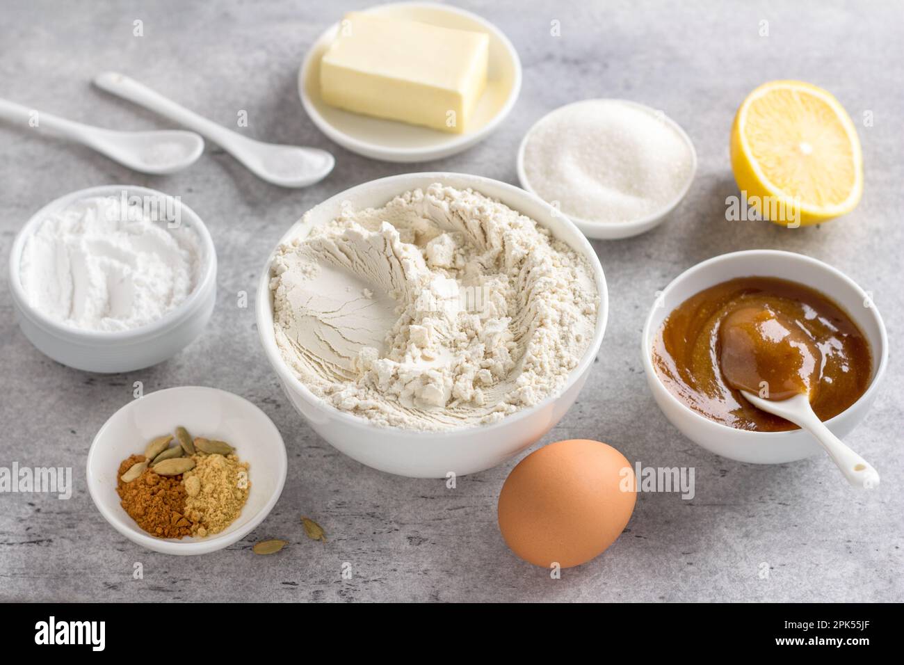 Ingrédients pour faire du pain d'épice au miel cuit à la vapeur : farine de blé, miel, œuf, beurre, sucre, sucre en poudre, citron, poudre à pâte, épices, sur un dos gris Banque D'Images