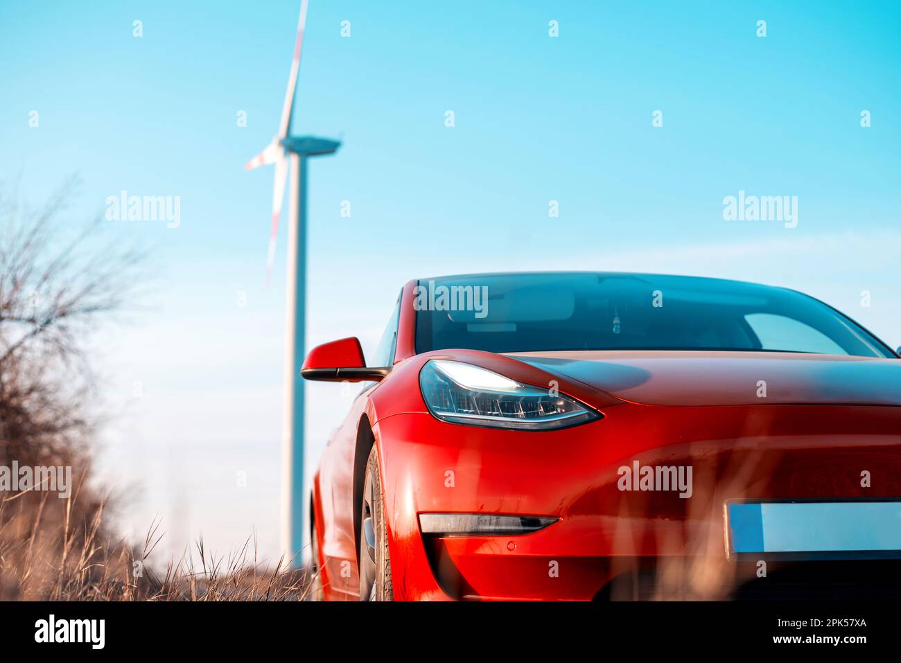 Vue sur une voiture électrique rouge garée. Éolienne en arrière-plan Photo  Stock - Alamy