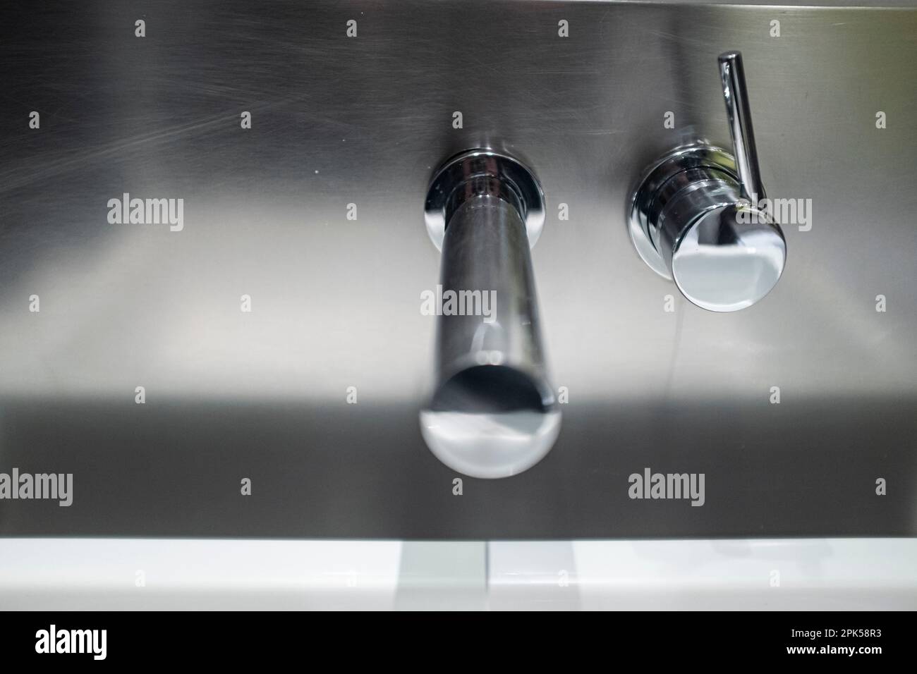 Robinet d'eau du robinet en argent au design moderne sur un mur en chrome Banque D'Images