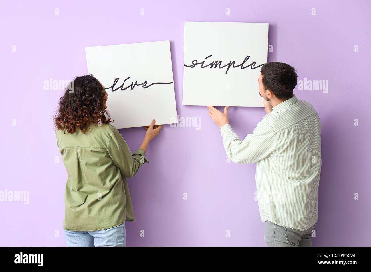 Jeunes couples accrochant des affiches sur un mur de lilas Banque D'Images