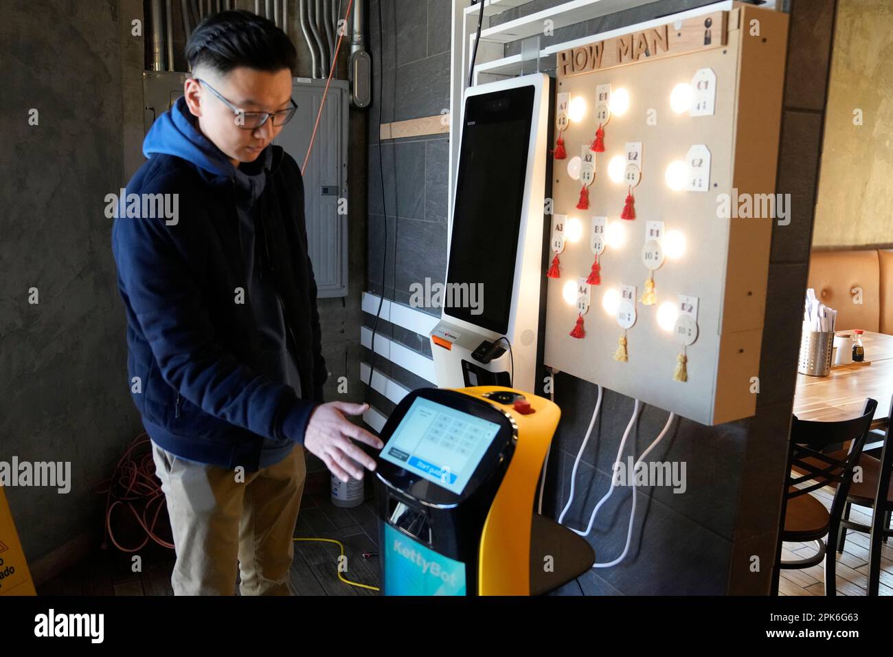 Li Zhai of the Noodle Topia restaurant points out features on his BellaBot robot, Monday, March 20, 2023 in Madison Heights, Mich. Zhai was having trouble finding staff for the restaurant in the summer of 2021, so he bought a robot which was so successful he added two more. With the robots, Zhai only needs three workers to do the same volume of business that five or six people used to handle. (AP Photo/Carlos Osorio) Banque D'Images