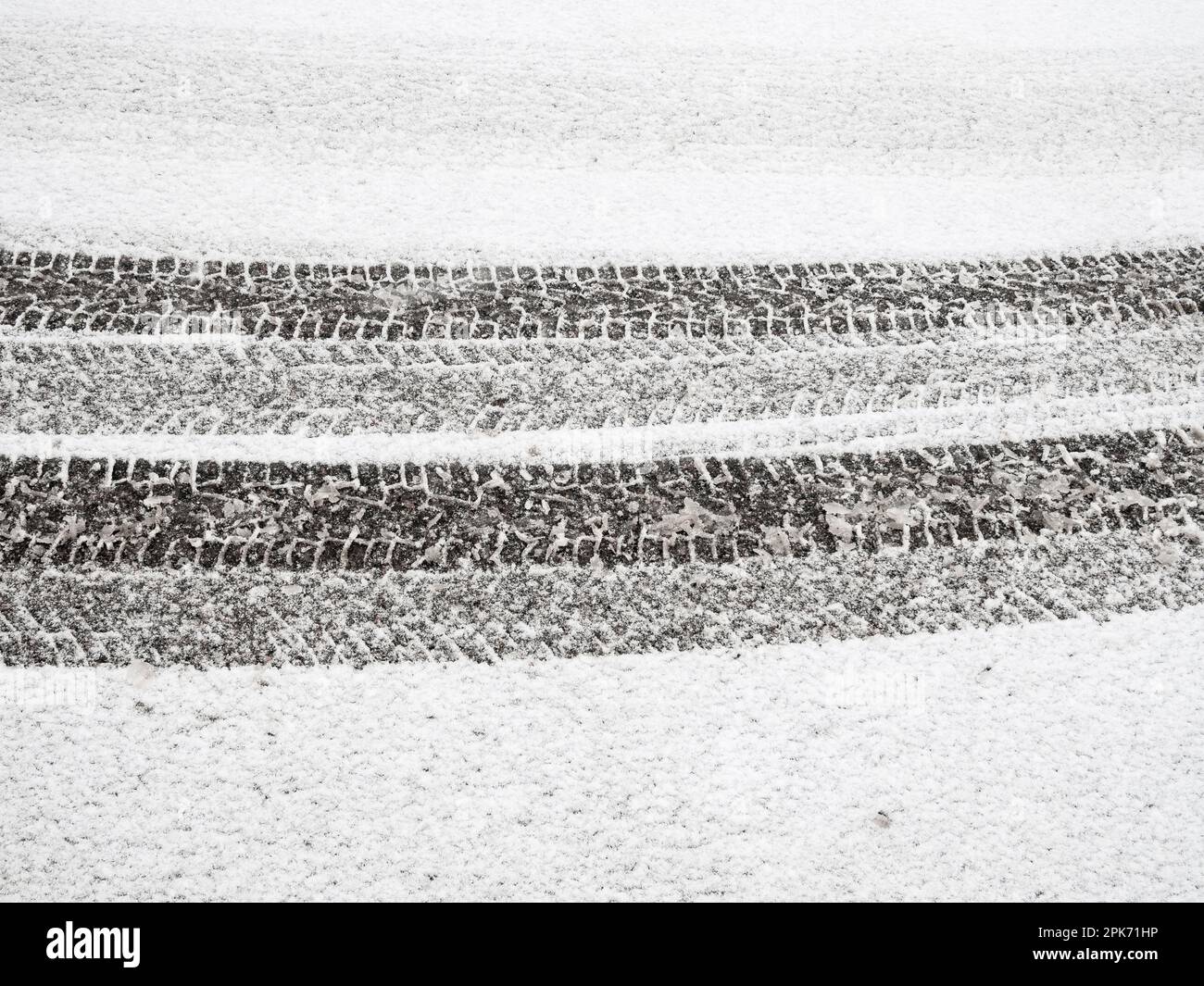 La neige fraîche et intacte couvre la rue d'hiver. Les marques des pneus créent un motif de lignes errantes sur la place de stationnement blanche et nette. Banque D'Images