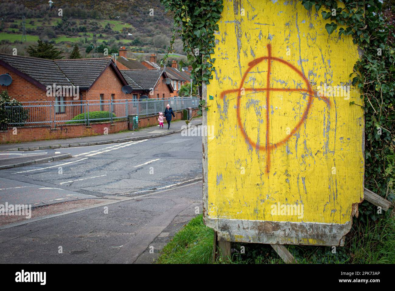 IRLANDE DU NORD - Une femme avec un enfant passe devant des graffitis loyalistes menaçants dans l'ouest de Belfast . Banque D'Images