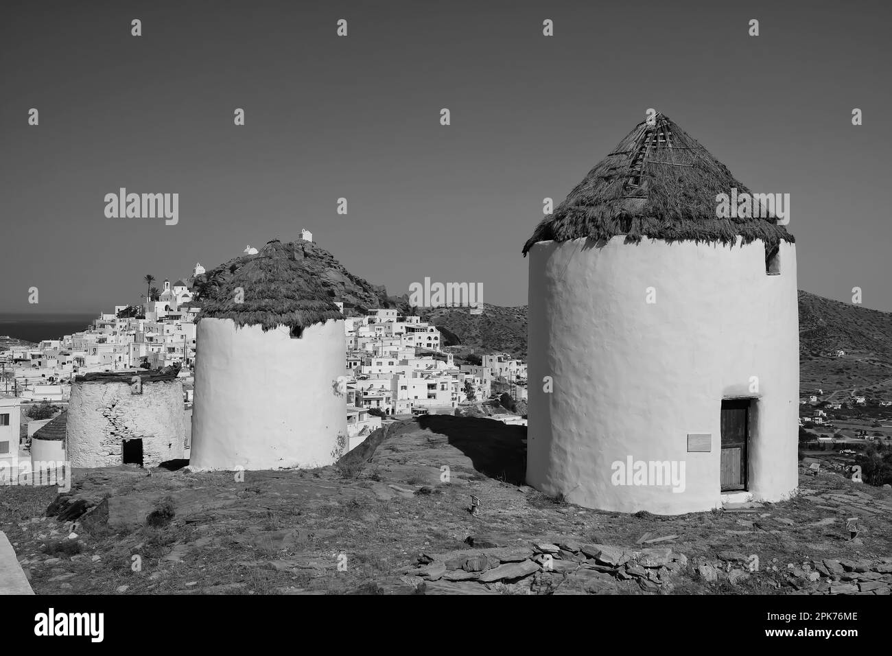 Vue sur un magnifique moulin blanc et le village d'iOS Grèce en arrière-plan en noir et blanc Banque D'Images