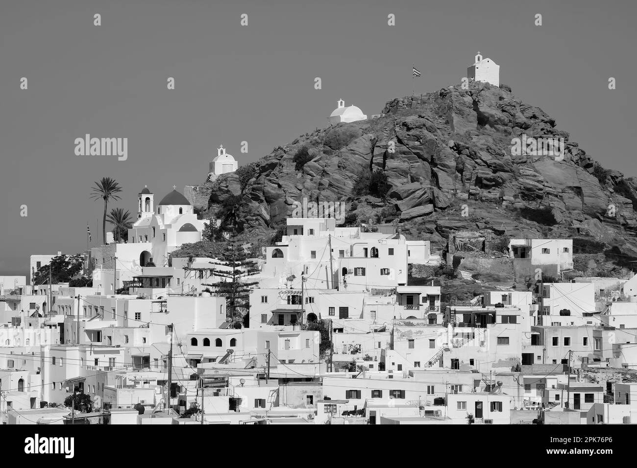 Vue panoramique d'une église, de petites chapelles et du drapeau grec sur le sommet d'une colline surplombant la mer Égée à iOS en Grèce, également connu sous le nom de Chora Banque D'Images