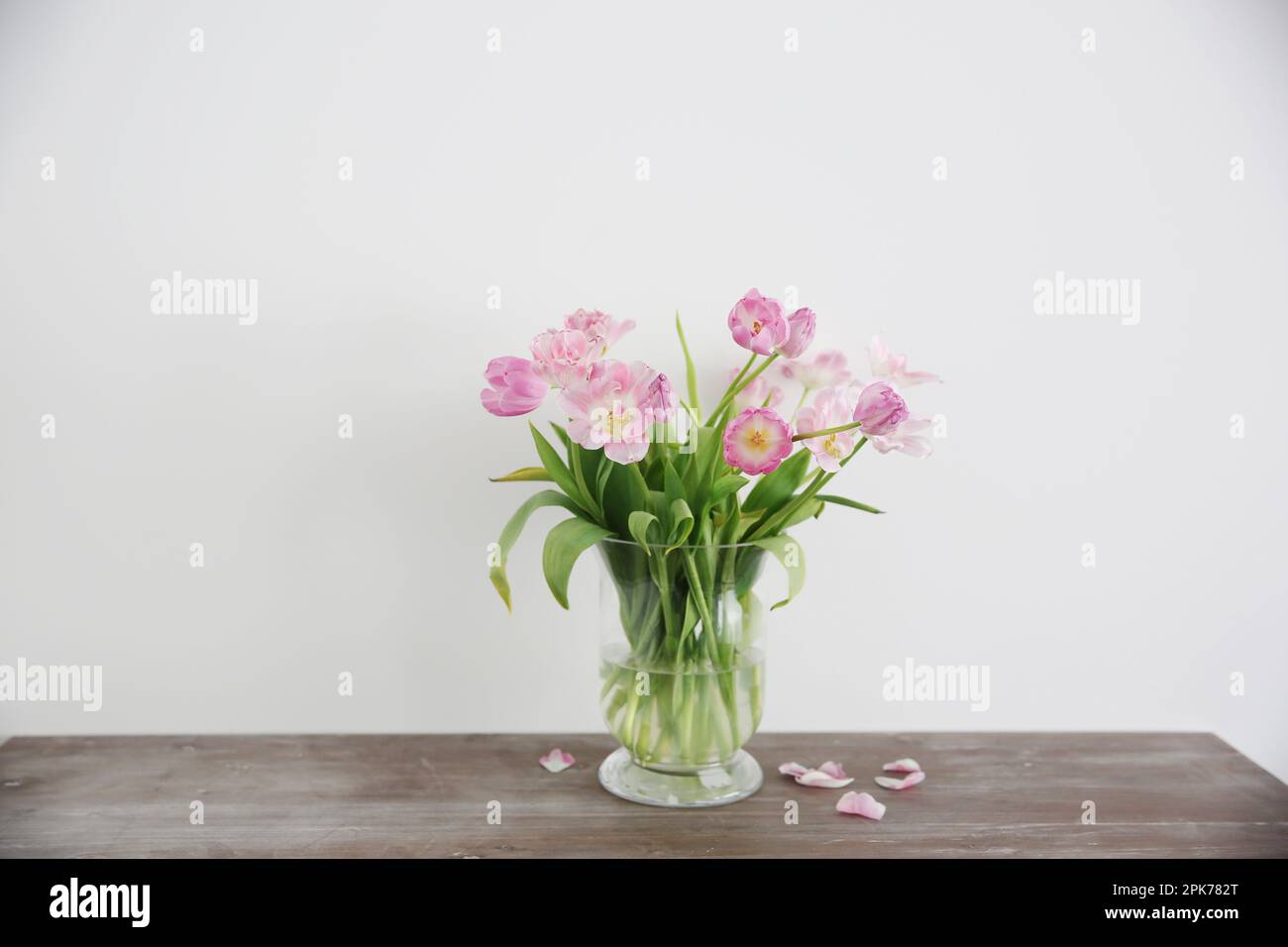 Bouquet de fleurs de tulipes roses dans un vase sur une table en bois. Banque D'Images
