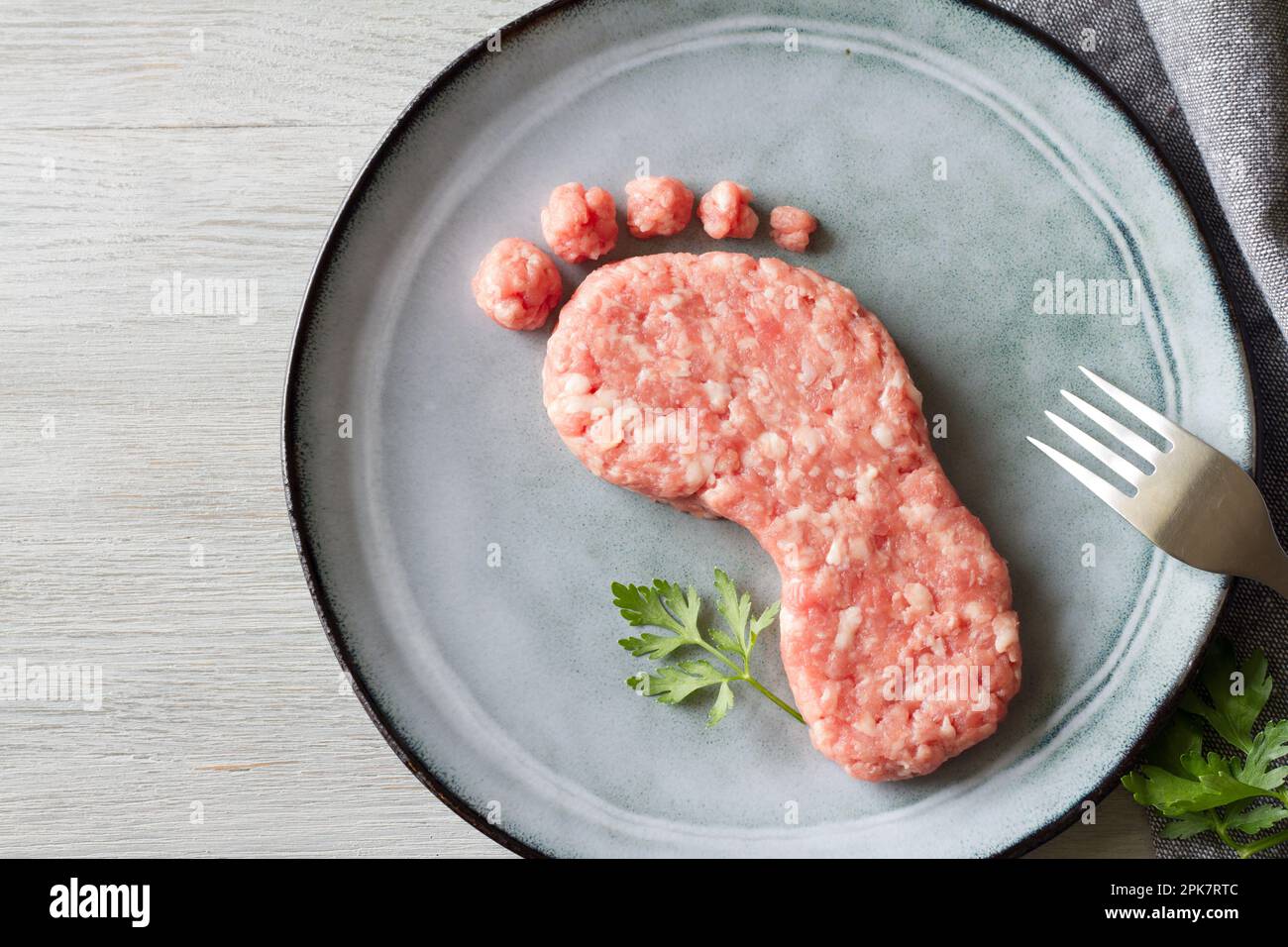 Concept d'empreinte carbone, consommation de viande et émissions de CO2, viande sur plaque en forme de pied, abstraction Banque D'Images