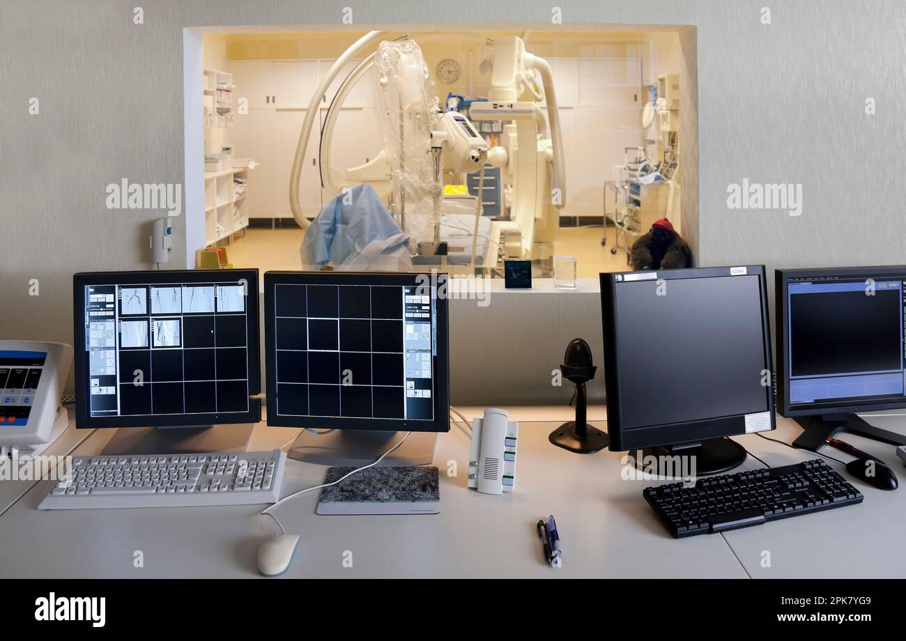 Une chambre d'hôpital moderne, un grand scanner portable avec bras incurvés et bancs d'écrans pour l'imagerie médicale, vue depuis le contr Banque D'Images