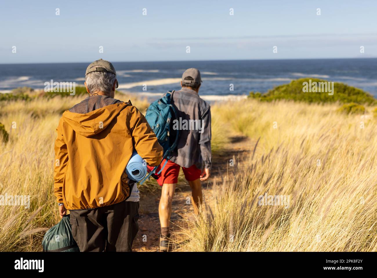Couple biracial senior marchant avec sac à dos et équipement de camping au bord de la mer Banque D'Images