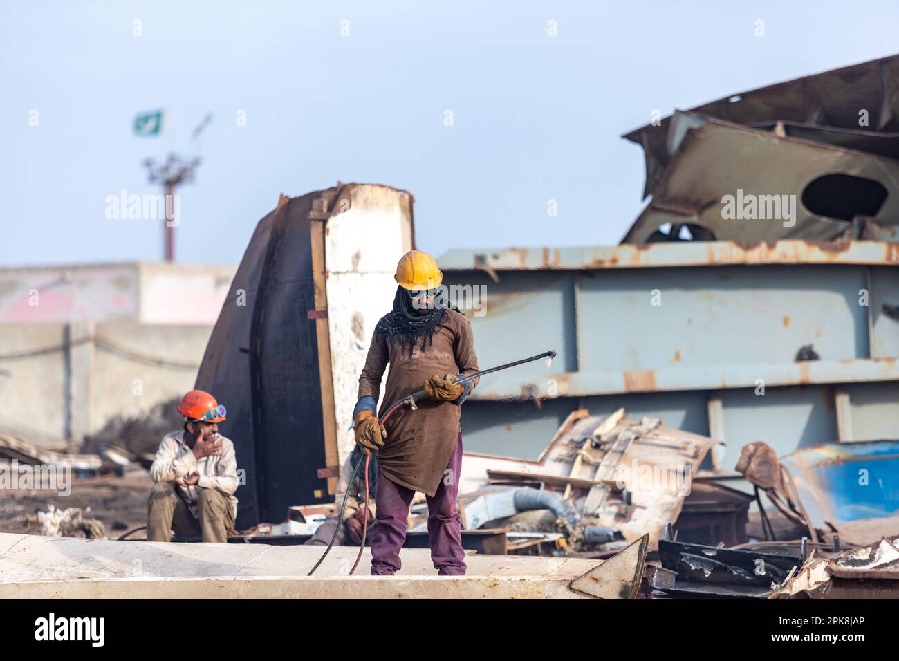 Gadani Pakistan août 2021, un travailleur portant un casque de sécurité jaune coupant une tôle avec un arc de soudage au chantier de démolition de navire de Gadani Banque D'Images