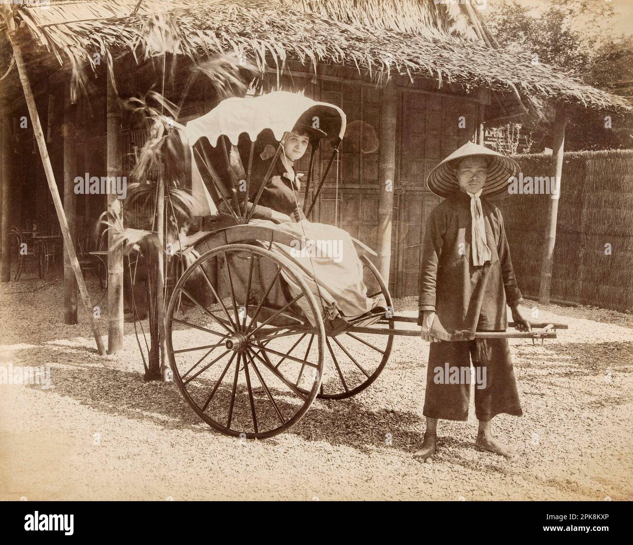 Exposition universelle de 1889 - Homme en costume chinois tirant un pousse-pousse où une femme est assise, champs-de-Mars, 7th arrondissement, Paris Banque D'Images