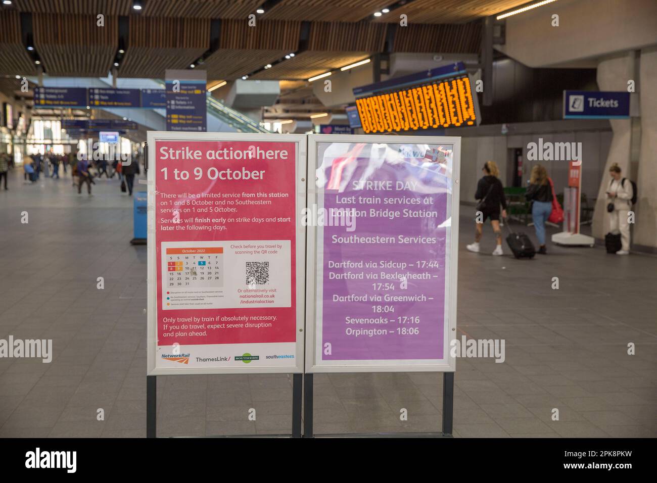 Les gens marchent devant un panneau d'information informant les passagers de l'action industrielle à la gare de London Bridge à Londres. Banque D'Images