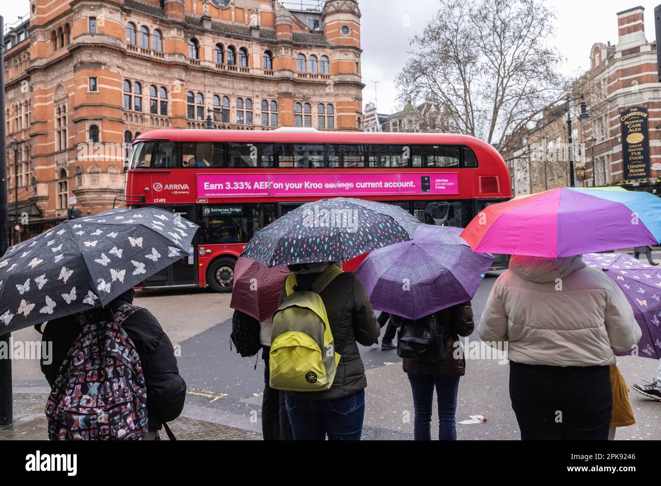 Les touristes du centre de Londres prennent refuge sous des parasols en face du Palace Theatre à Cambridge Circus, West End Londres, Angleterre, Royaume-Uni Banque D'Images