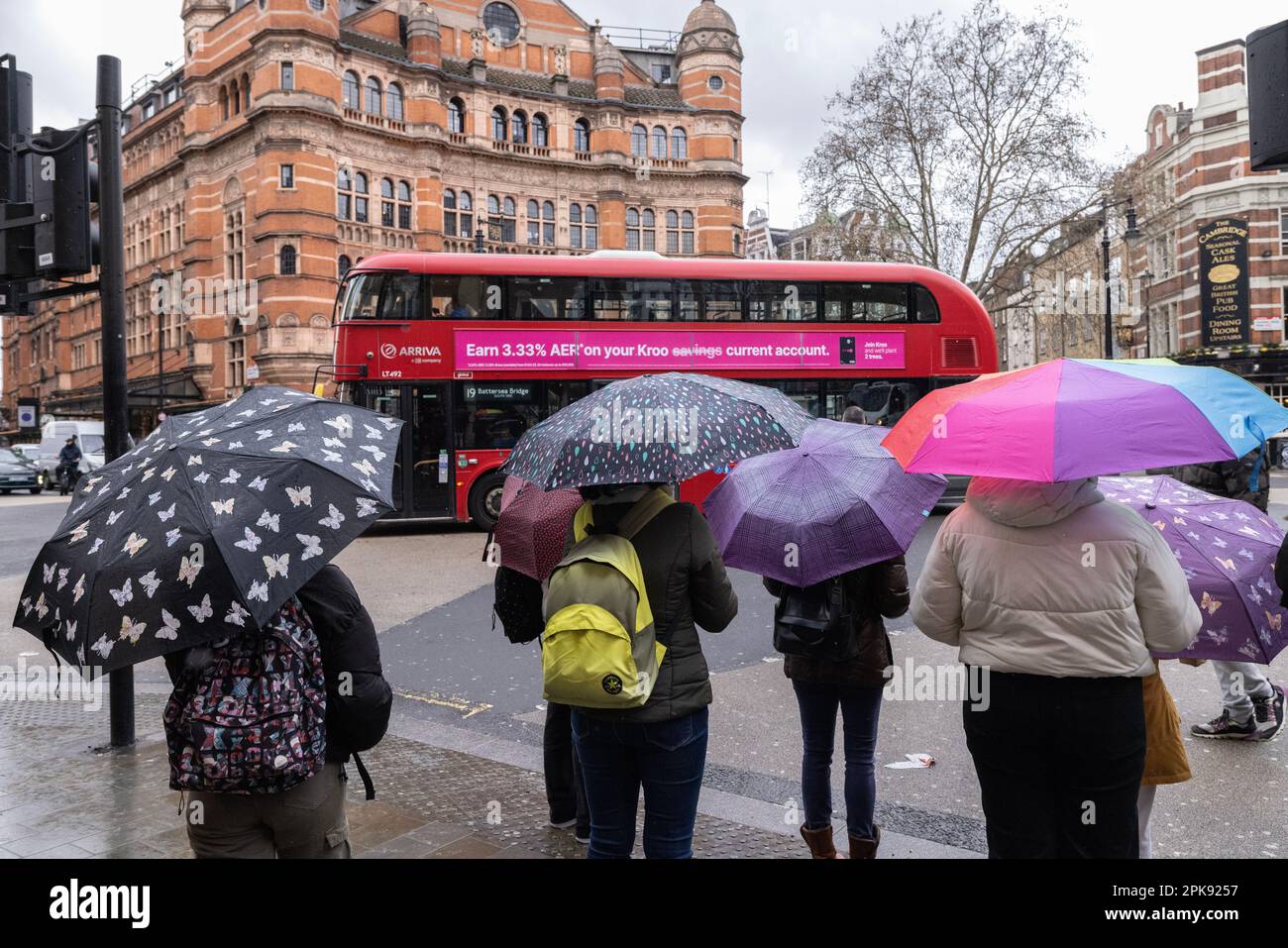 Les touristes du centre de Londres prennent refuge sous des parasols en face du Palace Theatre à Cambridge Circus, West End Londres, Angleterre, Royaume-Uni Banque D'Images