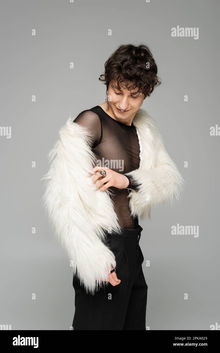 brunette personne non binaire portant une veste blanche en fausse fourrure isolee sur image grise Photo Stock Alamy