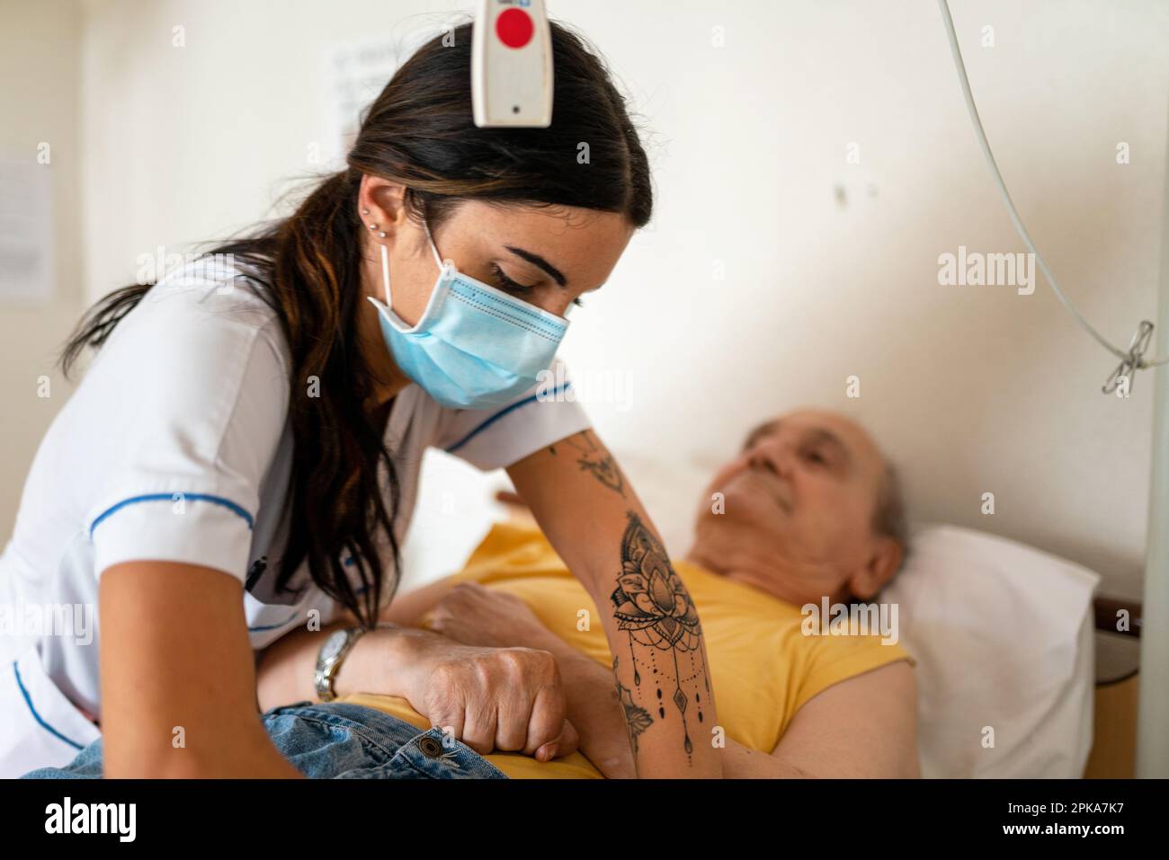 Soignant préparant le coucher d'un patient handicapé dans sa chambre à la maison de retraite. Banque D'Images