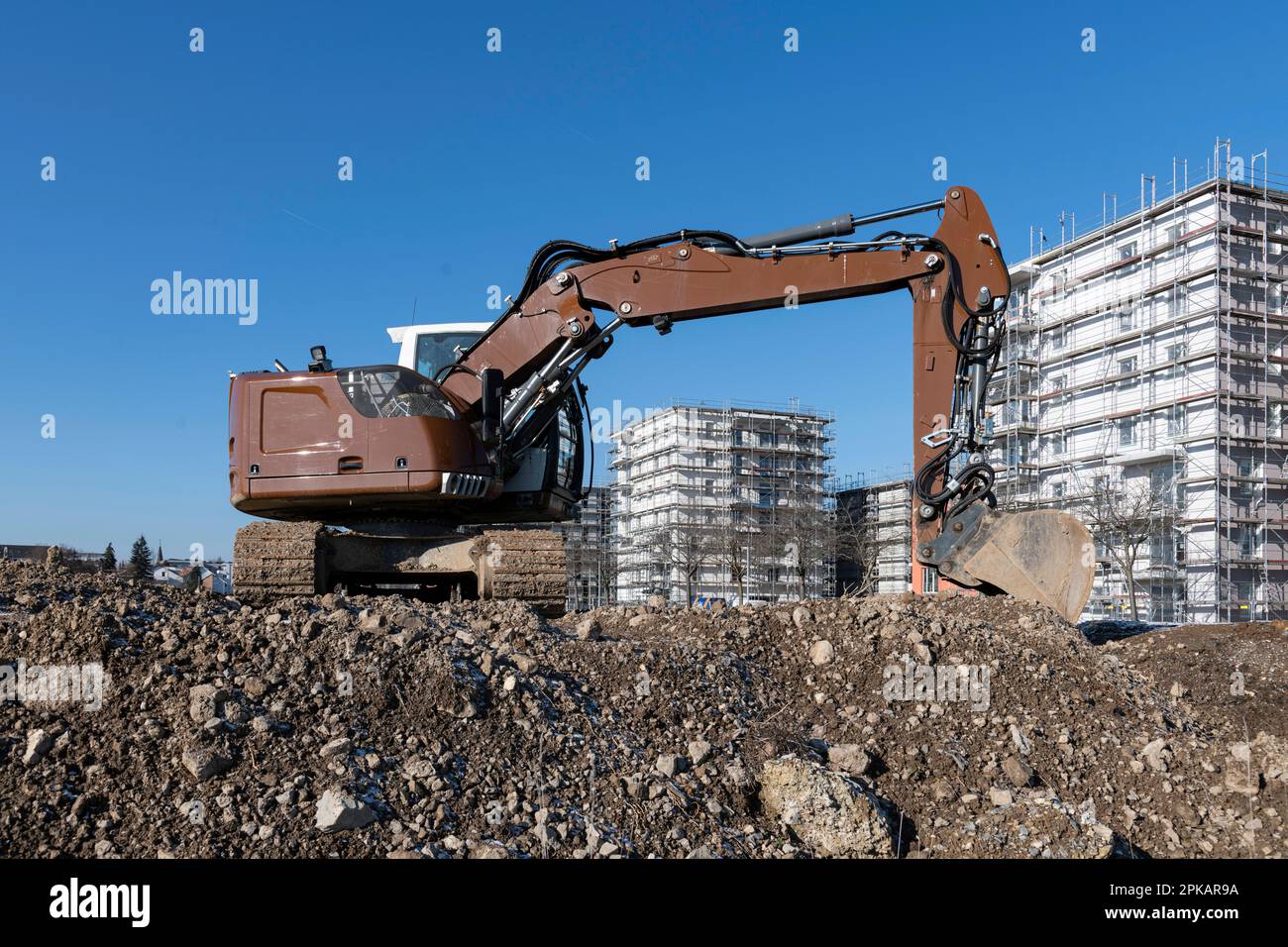 La pelle hydraulique marron se trouve sur un grand chantier de construction avec des bâtiments de construction à plusieurs étages en arrière-plan Banque D'Images