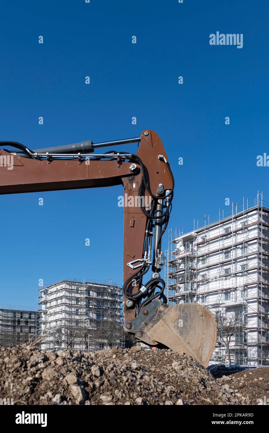 Pelle de pelle hydraulique brune se trouve sur un grand chantier de construction avec des bâtiments en coquille de plusieurs étages en arrière-plan Banque D'Images
