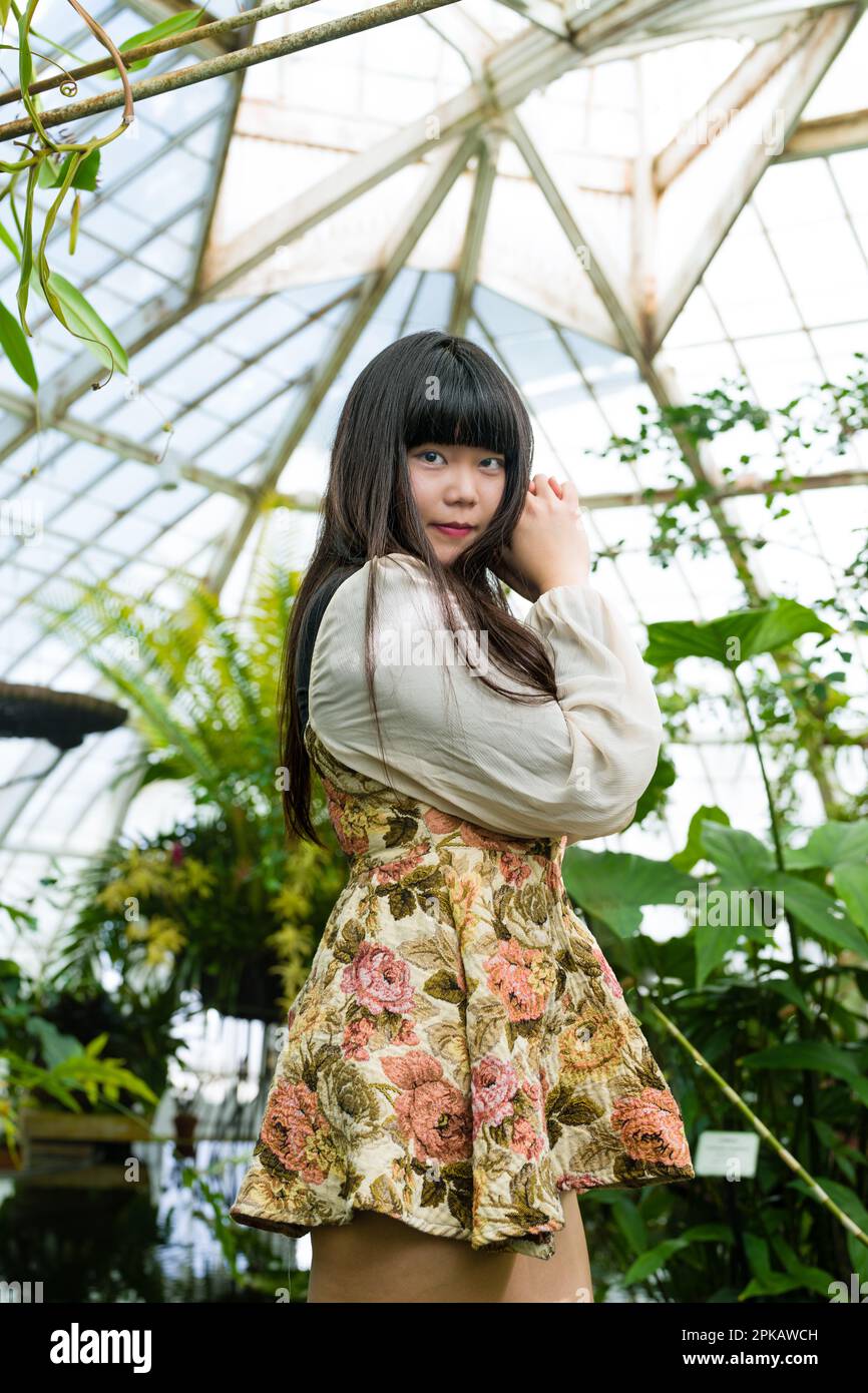 Jeune femme asiatique dans une serre tropicale | Robe à imprimé fleuri court | Conservatoire de fleurs Banque D'Images