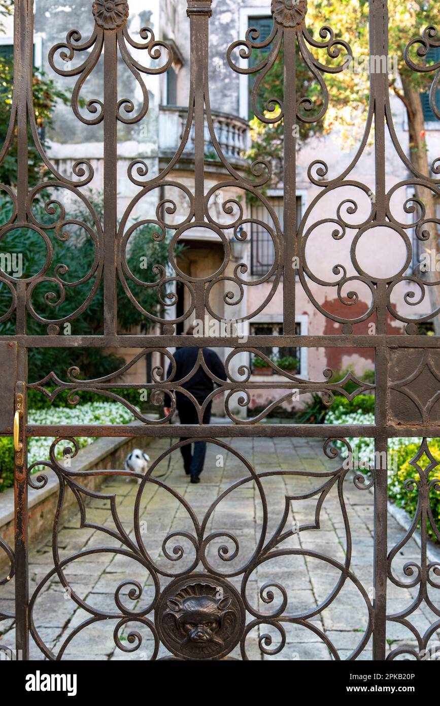 Homme avec chien aller pour une promenade, vue à travers une porte de fer, Venise, Italie Banque D'Images