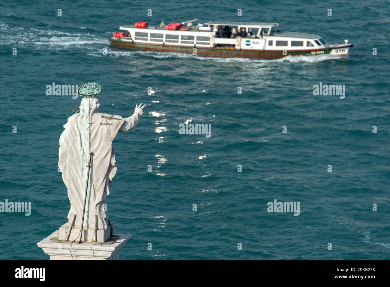 Sculpture de Jésus sur le toit de la Basilique de San Giorgio Maggiore en regardant vers le canal et un passage de Vaporetto, Venise, Italie Banque D'Images