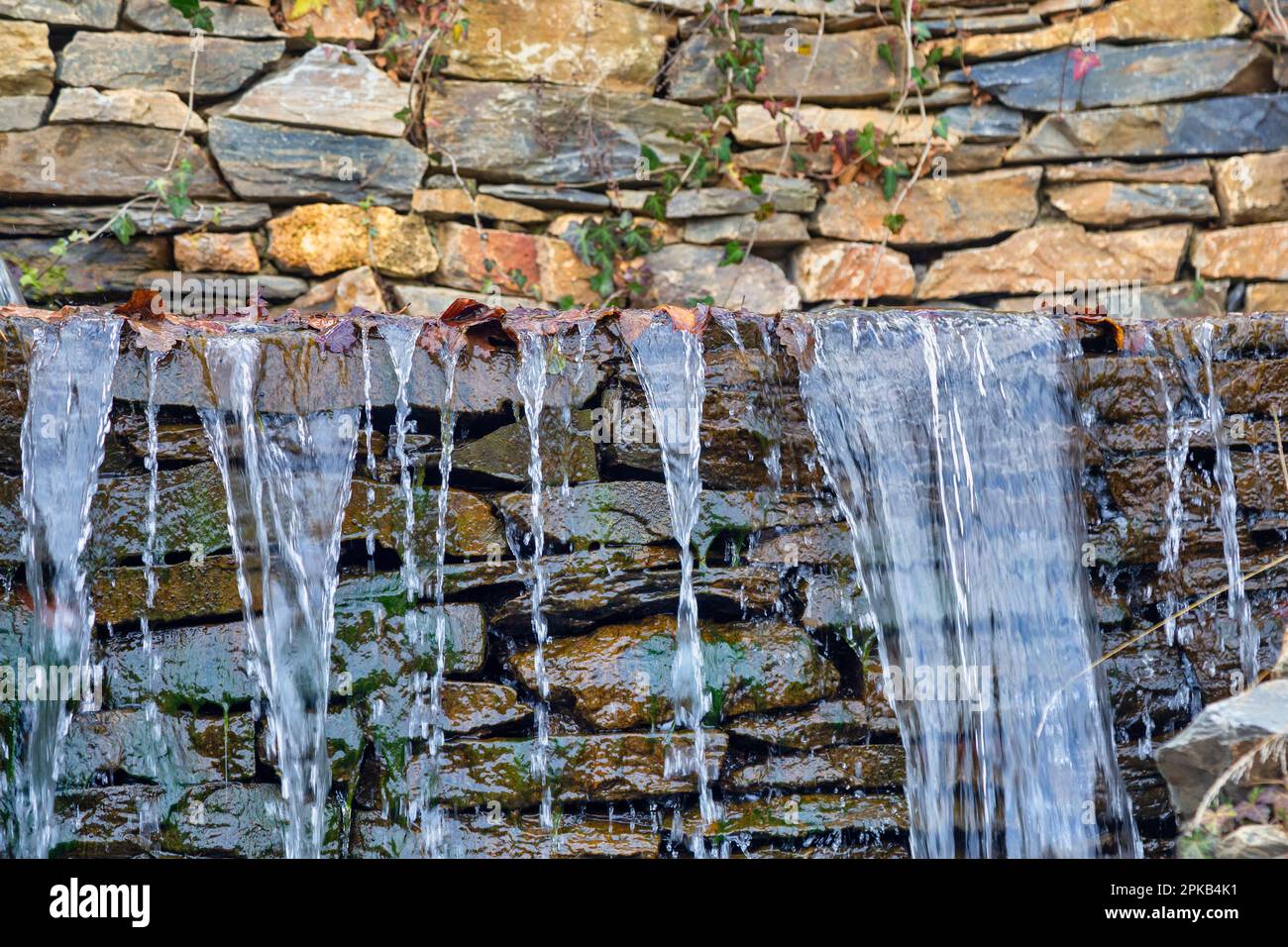 Des ruisseaux d'eau s'écoulent sur fond de pierres humides. Les gouttes d'eau tombent sur les pierres. Banque D'Images