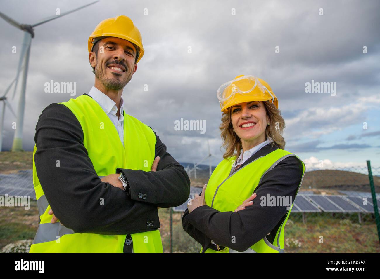 Deux ingénieurs souriants aux bras pliés dans une centrale solaire. Banque D'Images