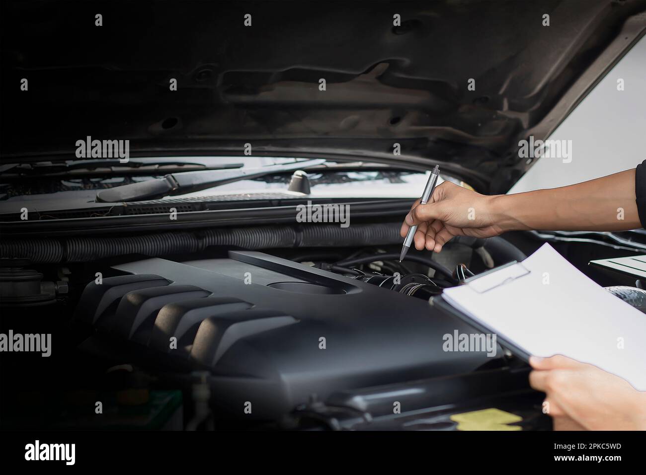 Mécanicien d'automobiles réparateur vérifiant un moteur de voiture avec l'inspection écrire dans le presse-papiers la liste de contrôle pour la machine de réparation, l'entretien de voiture et l'entretien Banque D'Images