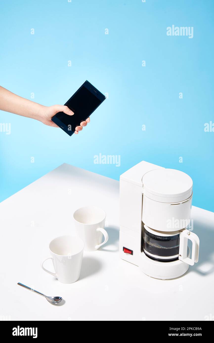 Téléphone intelligent fonctionnant avec une cafetière Banque D'Images