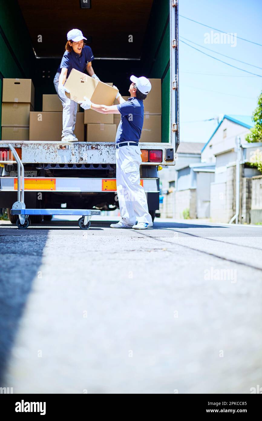 Homme et femme dans des vêtements de travail chargeant des boîtes en carton sur un camion dans une rue Banque D'Images