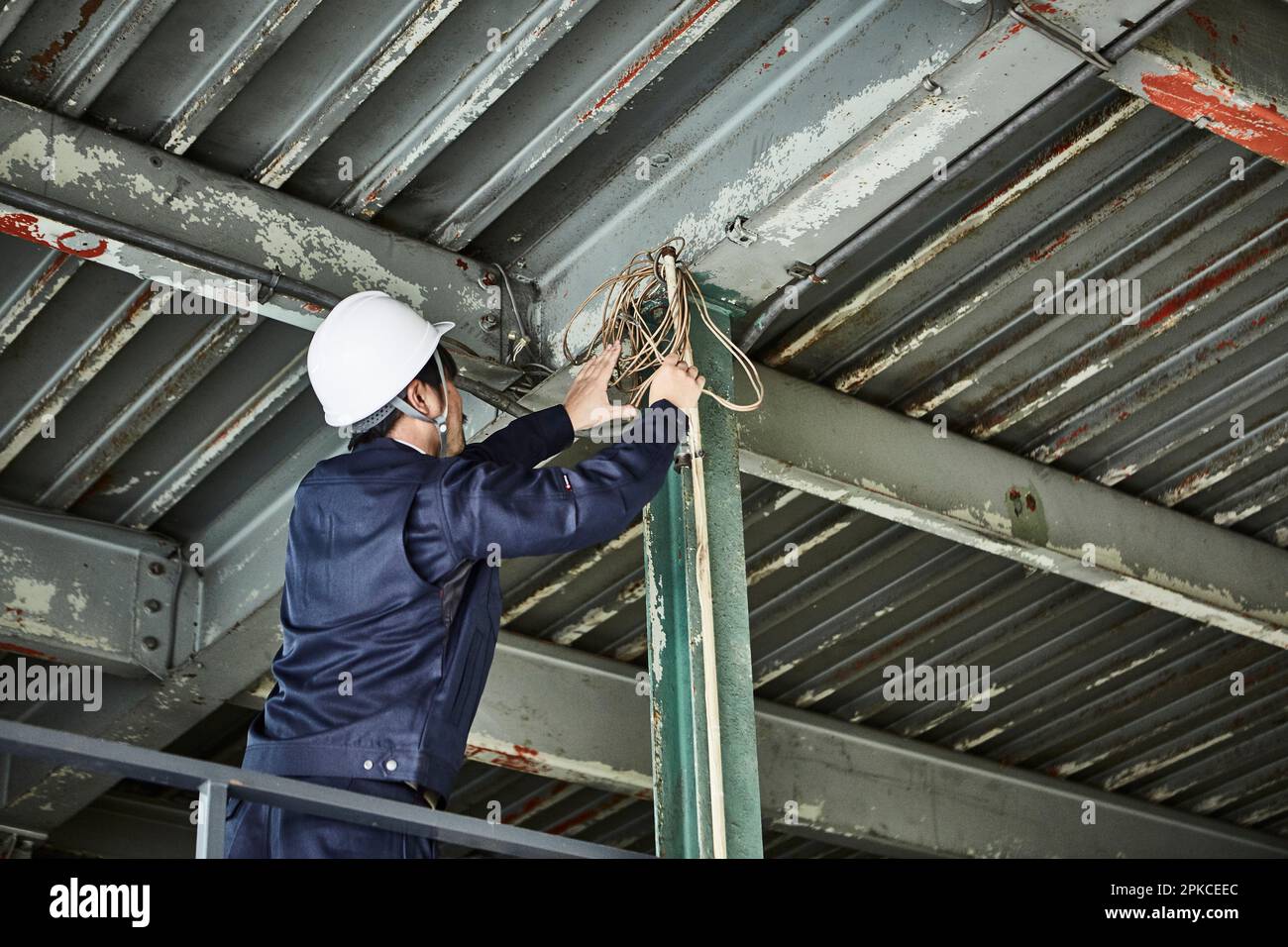 Homme dans les vêtements de travail et casque travaillant sur le cadre en acier Banque D'Images