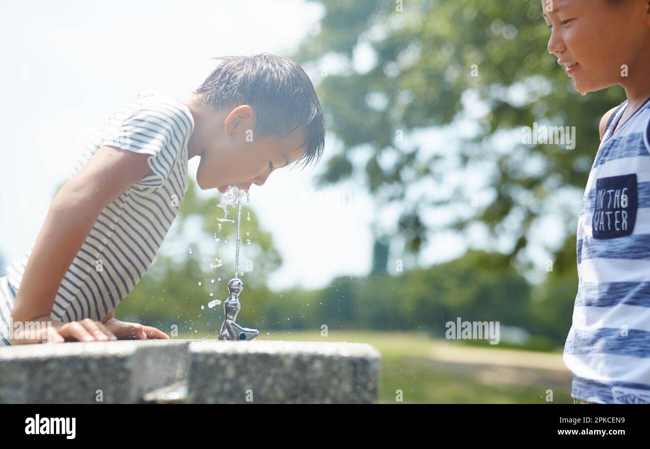 Garçon buvant de l'eau à la fontaine d'eau Banque D'Images