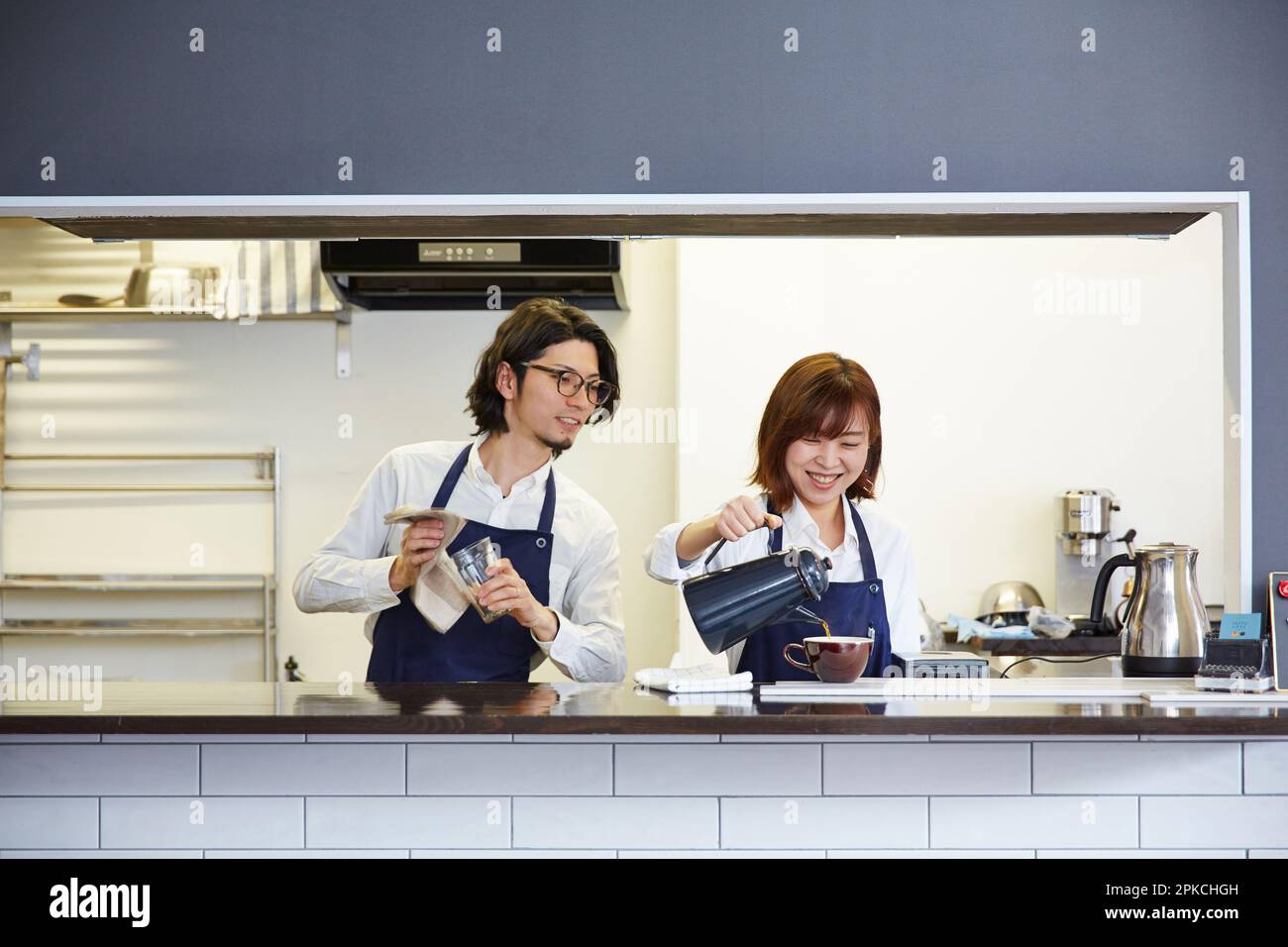 Une serveuse qui verse du café et une serveuse qui regarde Banque D'Images