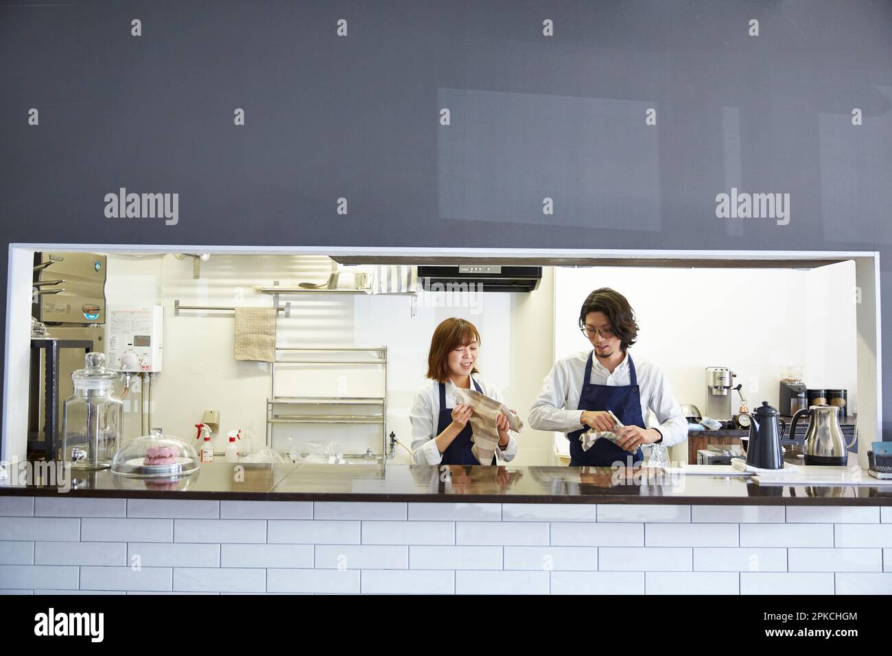 Une serveuse masculine et féminine qui polissage un verre de café Banque D'Images