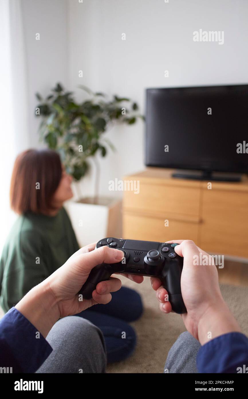 Une main masculine jouant à des jeux vidéo avec des amis dans le salon Banque D'Images
