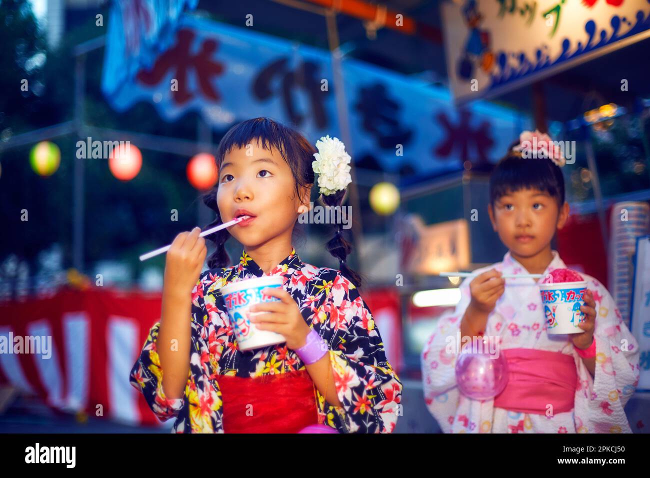 Fille de yukata mangeant de la glace rasée achetée dans un stand de festival Banque D'Images