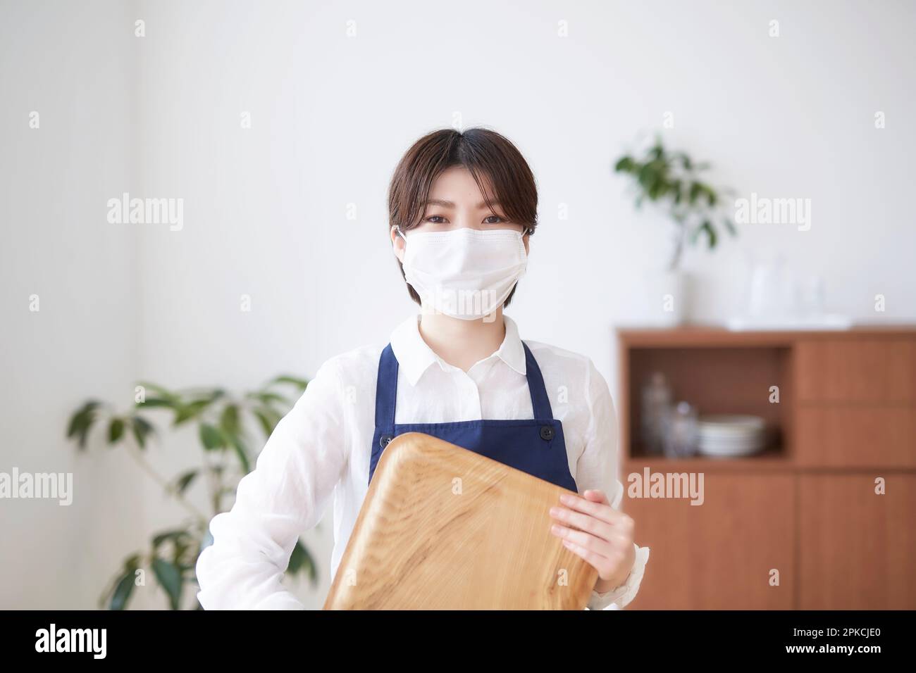 Femme masquée tenant le plateau à l'intérieur Banque D'Images