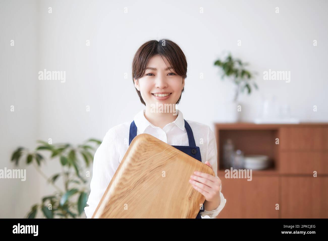 Femme souriante debout avec un plateau à l'intérieur Banque D'Images