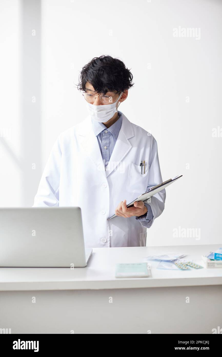 Homme en blanc travaillant à un ordinateur portable au-dessus du comptoir Banque D'Images
