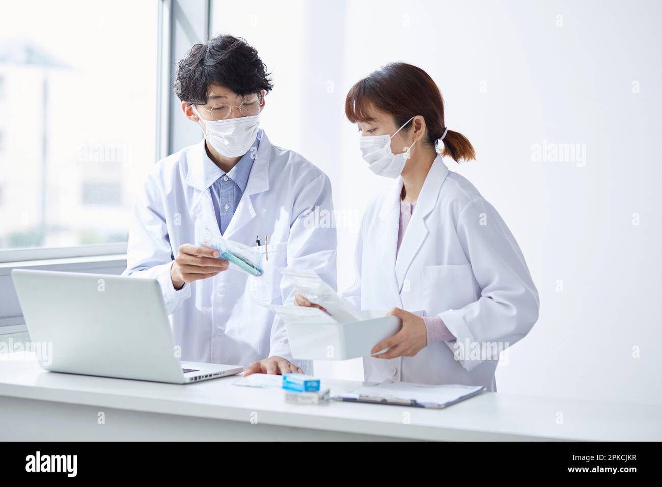 Homme et femme en blanc vérifiant la médecine tout en regardant l'ordinateur portable Banque D'Images
