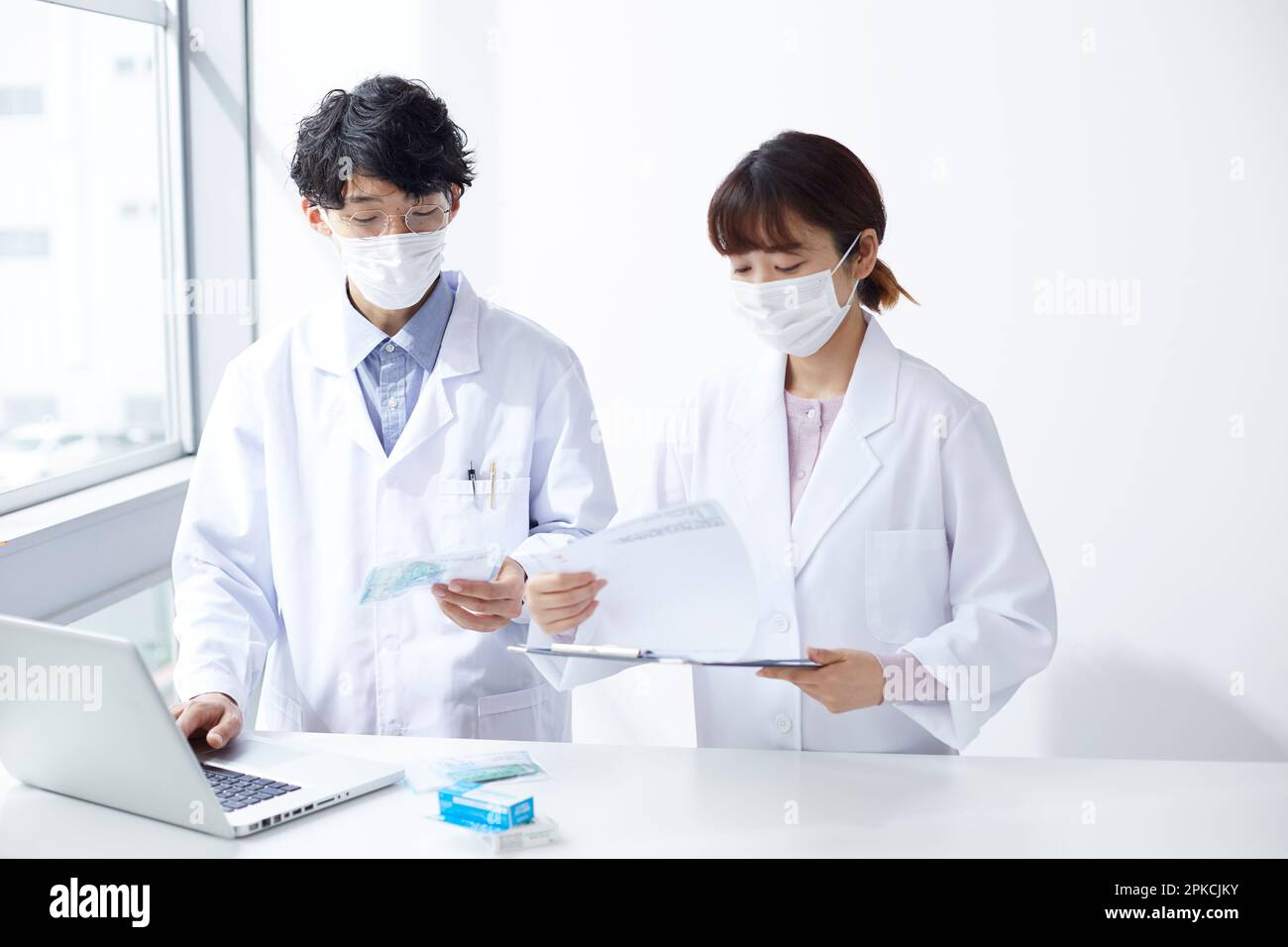Homme et femme en blanc vérifiant la médecine tout en regardant l'ordinateur portable Banque D'Images
