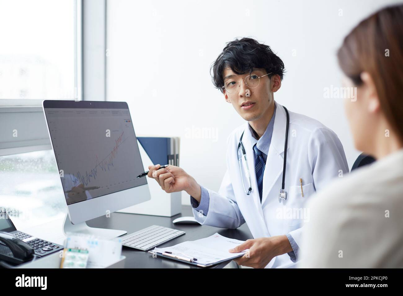 Homme en blanc expliquant devant un moniteur d'ordinateur Banque D'Images