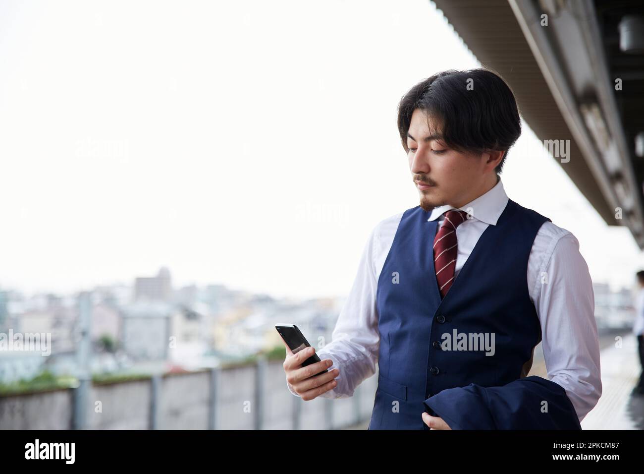 Homme en costume regardant le smartphone sur la plate-forme de la station Banque D'Images