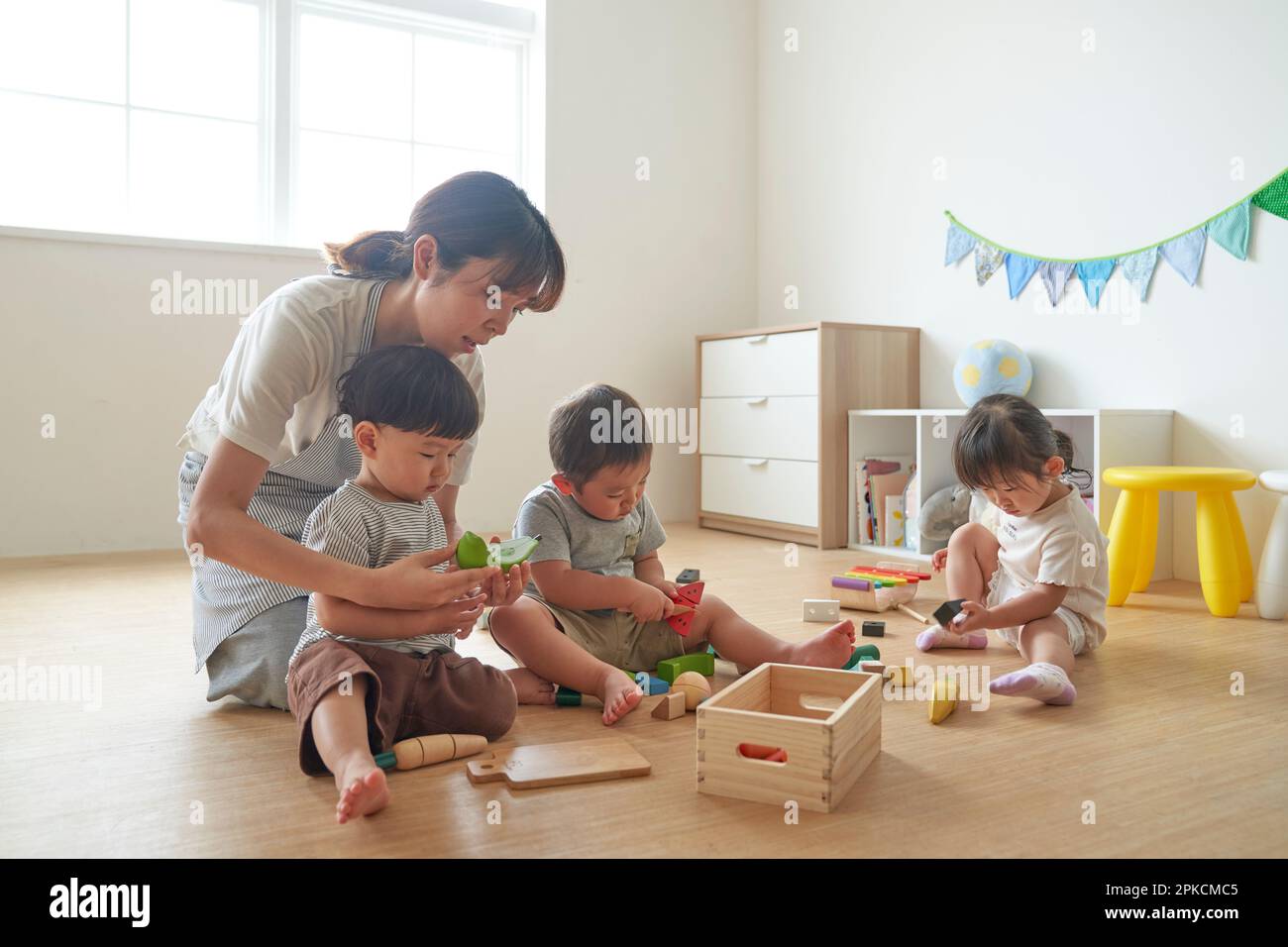 Une travailleuse de garde d'enfants avec des enfants jouant avec des jouets Banque D'Images