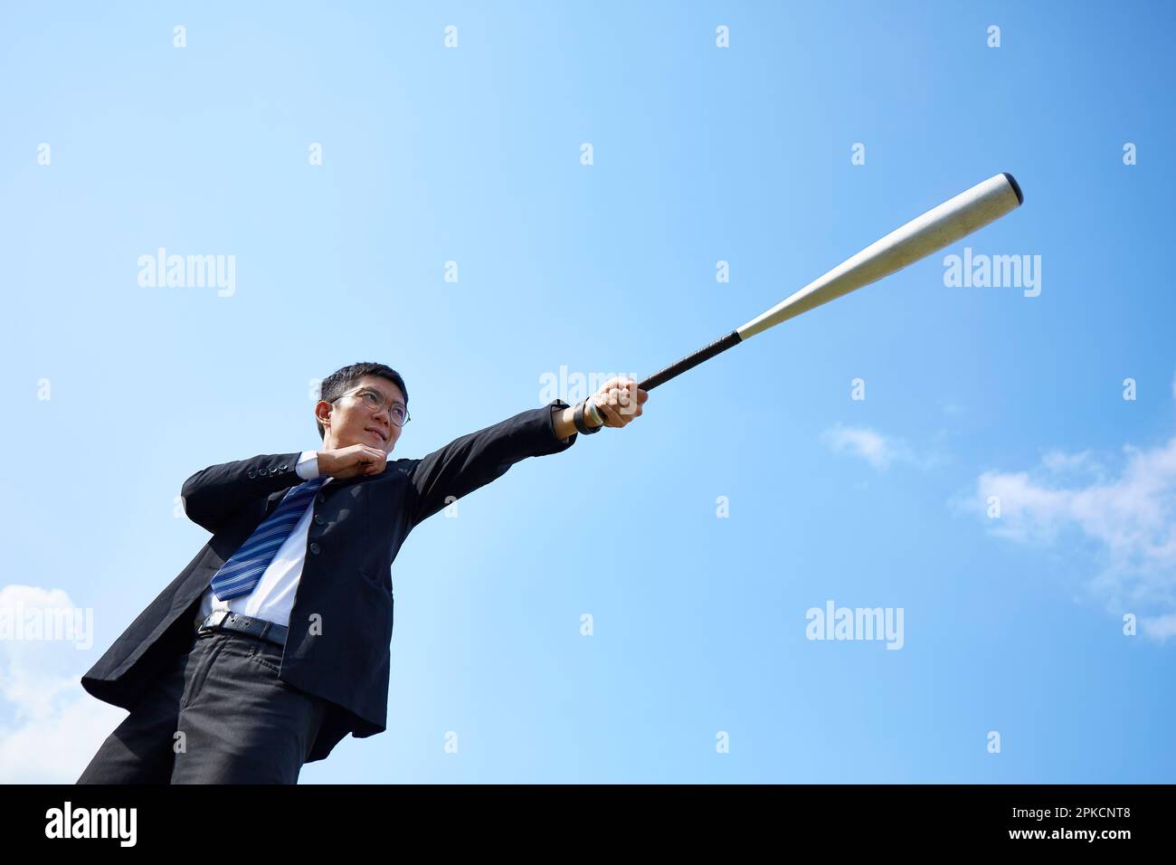 Homme en costume tenant une batte sous le ciel bleu Banque D'Images