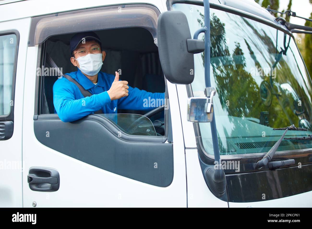 Homme portant des vêtements de travail et un masque conduisant un camion Banque D'Images
