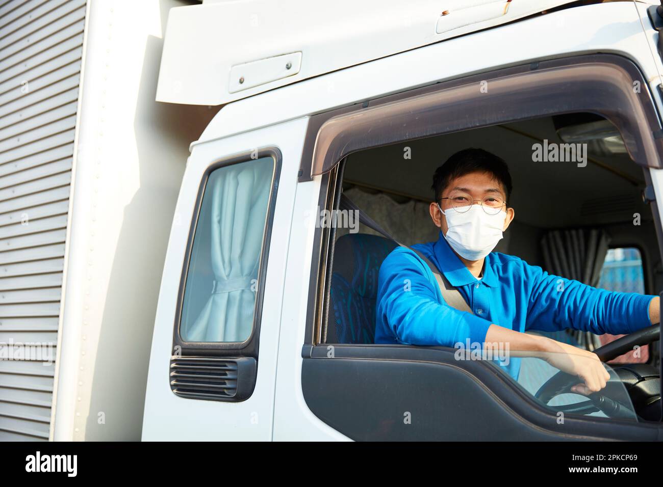 Homme dans les vêtements de travail et masque conduisant un camion Banque D'Images