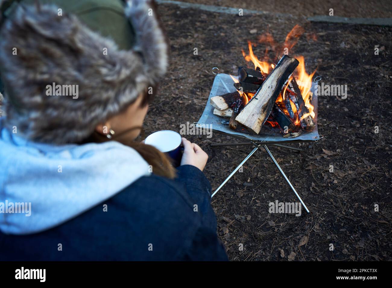 Femme assise devant un feu de camp dans un camp d'hiver Banque D'Images