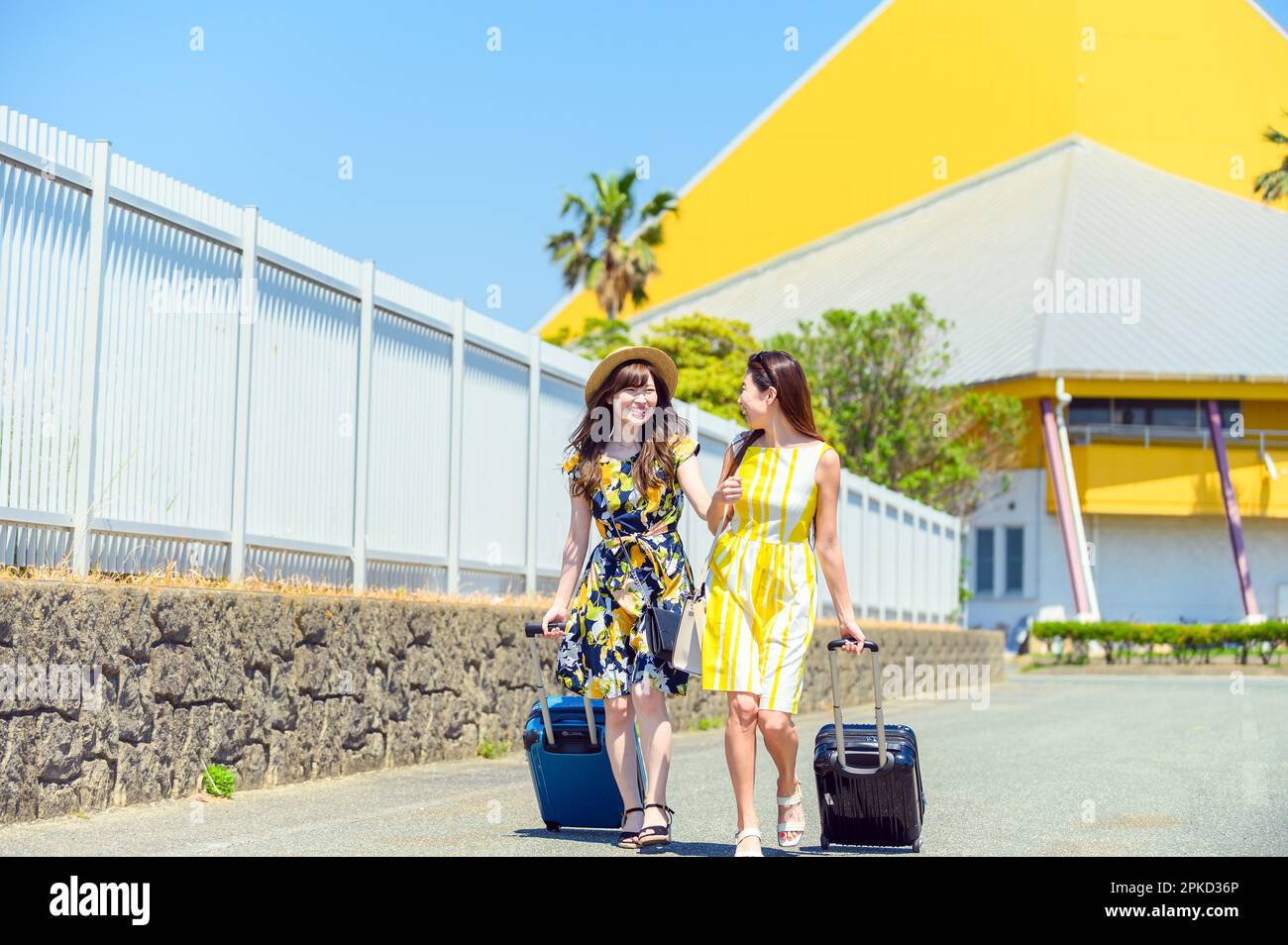 Deux femmes voyageant à bord d'une station balnéaire avec un bagage à main Banque D'Images