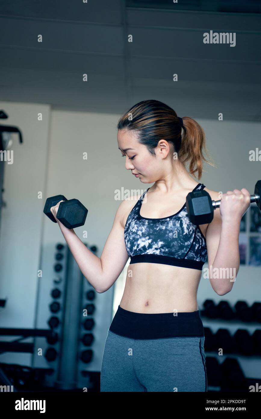 Femme faisant l'entraînement de force avec des haltères à la salle de gym Banque D'Images